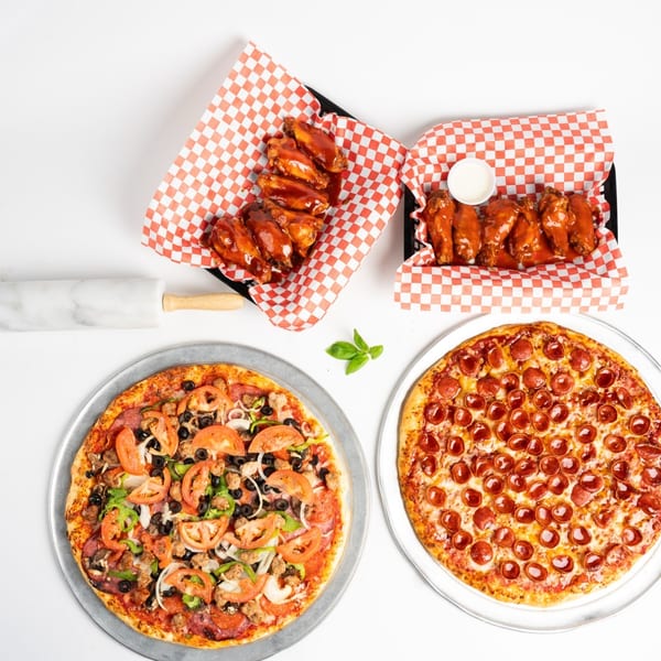 Two pizzas, one pepperoni and one supreme, with two baskets of buffalo wings on a white background.
