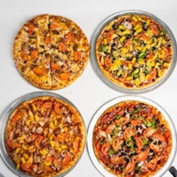 Four pizzas with various toppings, including vegetables and meats, on a white surface.